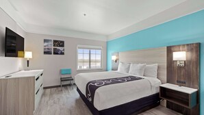 A modern hotel room with a bed, bedside tables, a desk, and a chair. - La Quinta Inn & Suites by Wyndham Raymondville (Raymondville)