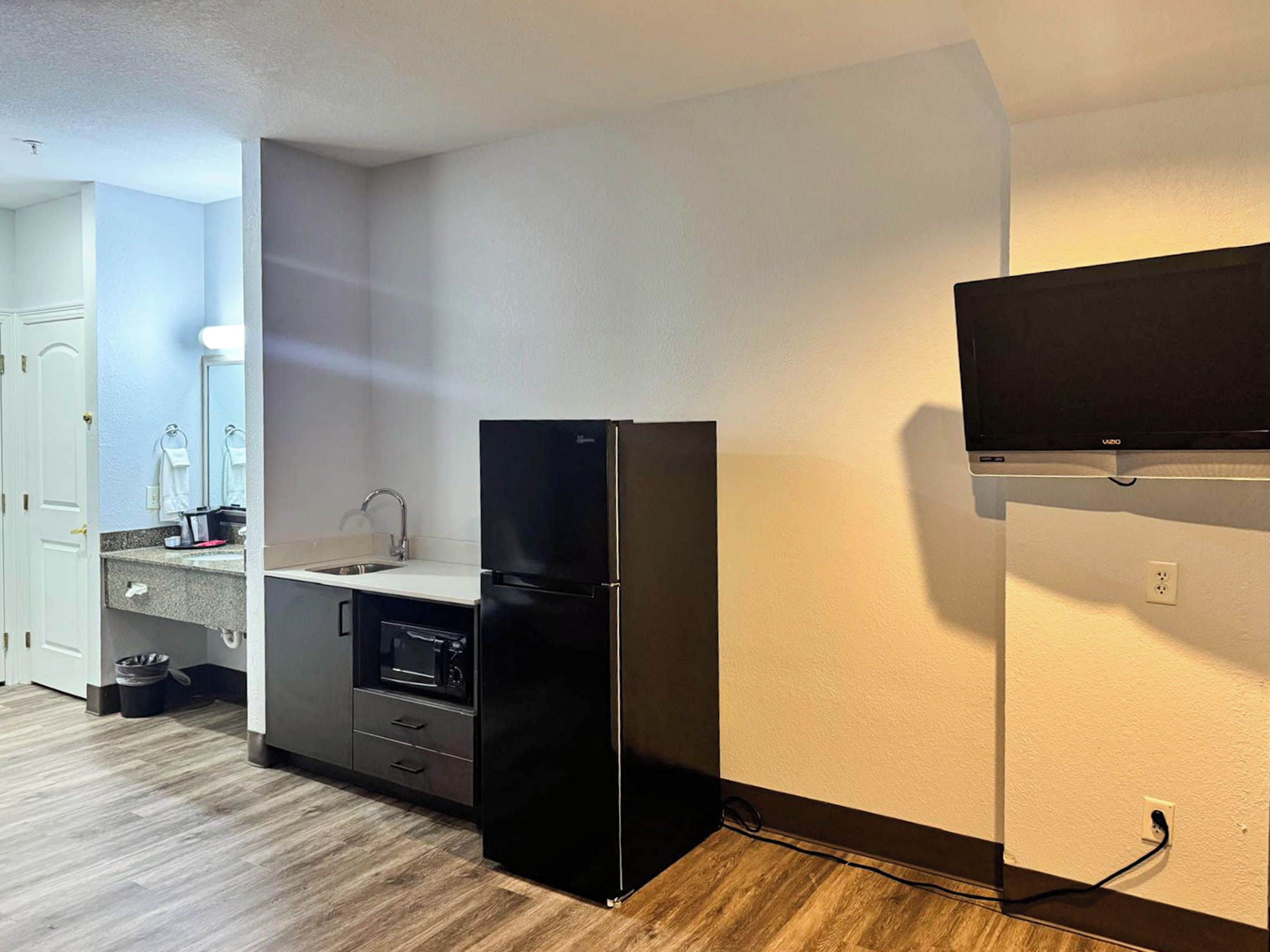 A compact kitchen with a refrigerator, a microwave, and a sink.
