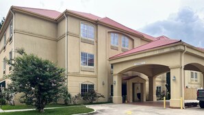 A multi-story hotel with a beige facade, red-tiled roof, and a covered entrance area.