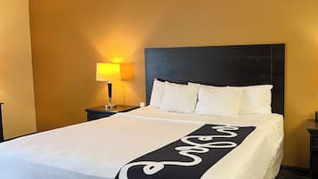 A hotel room with a bed, a nightstand with a lamp, and a headboard.