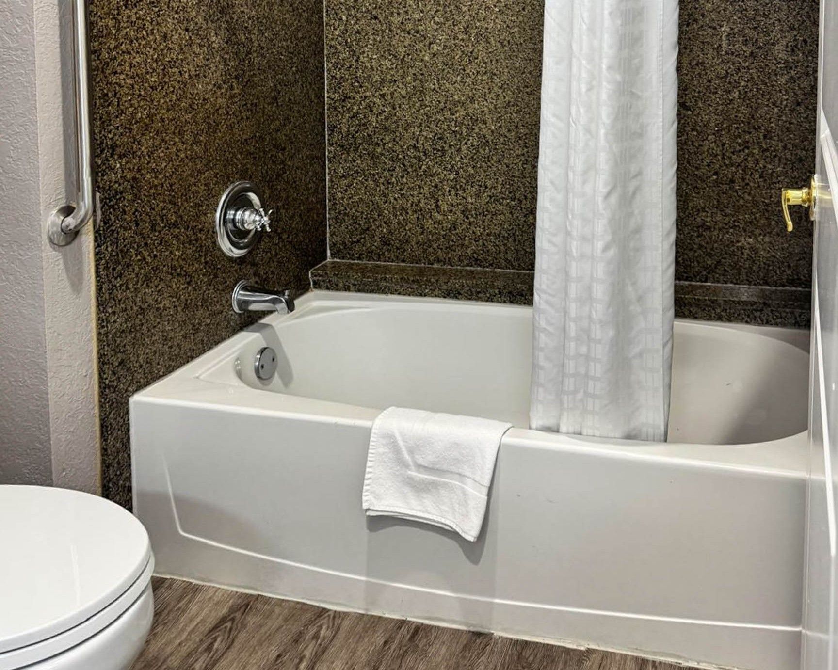 A bathroom with a bathtub, toilet, and a shower curtain.