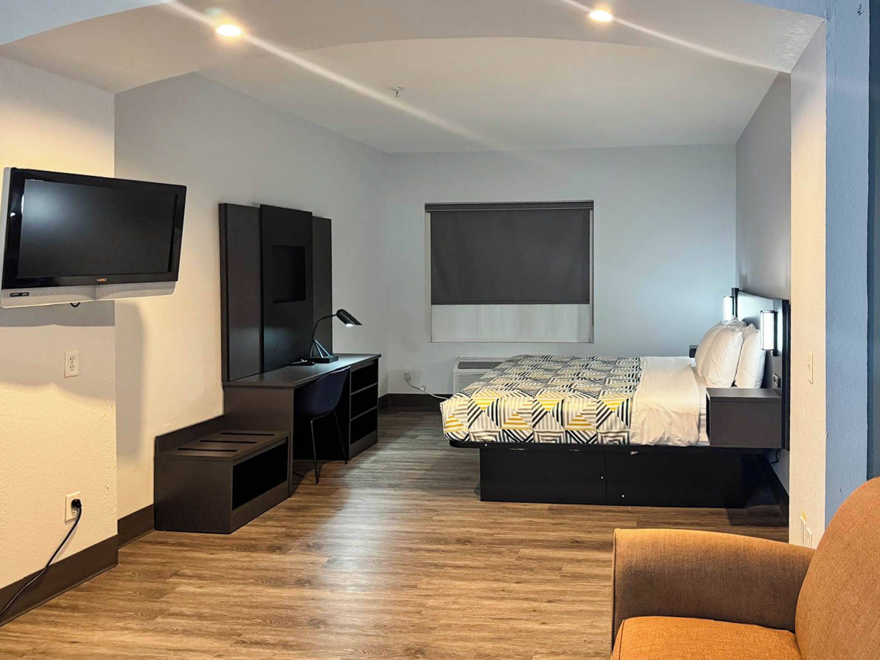 Habitació d'hotel senzilla amb llit, escriptori, cadira, televisió i finestra.