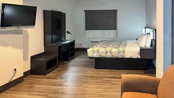 Habitació d'hotel senzilla amb llit, escriptori, cadira, televisió i finestra.