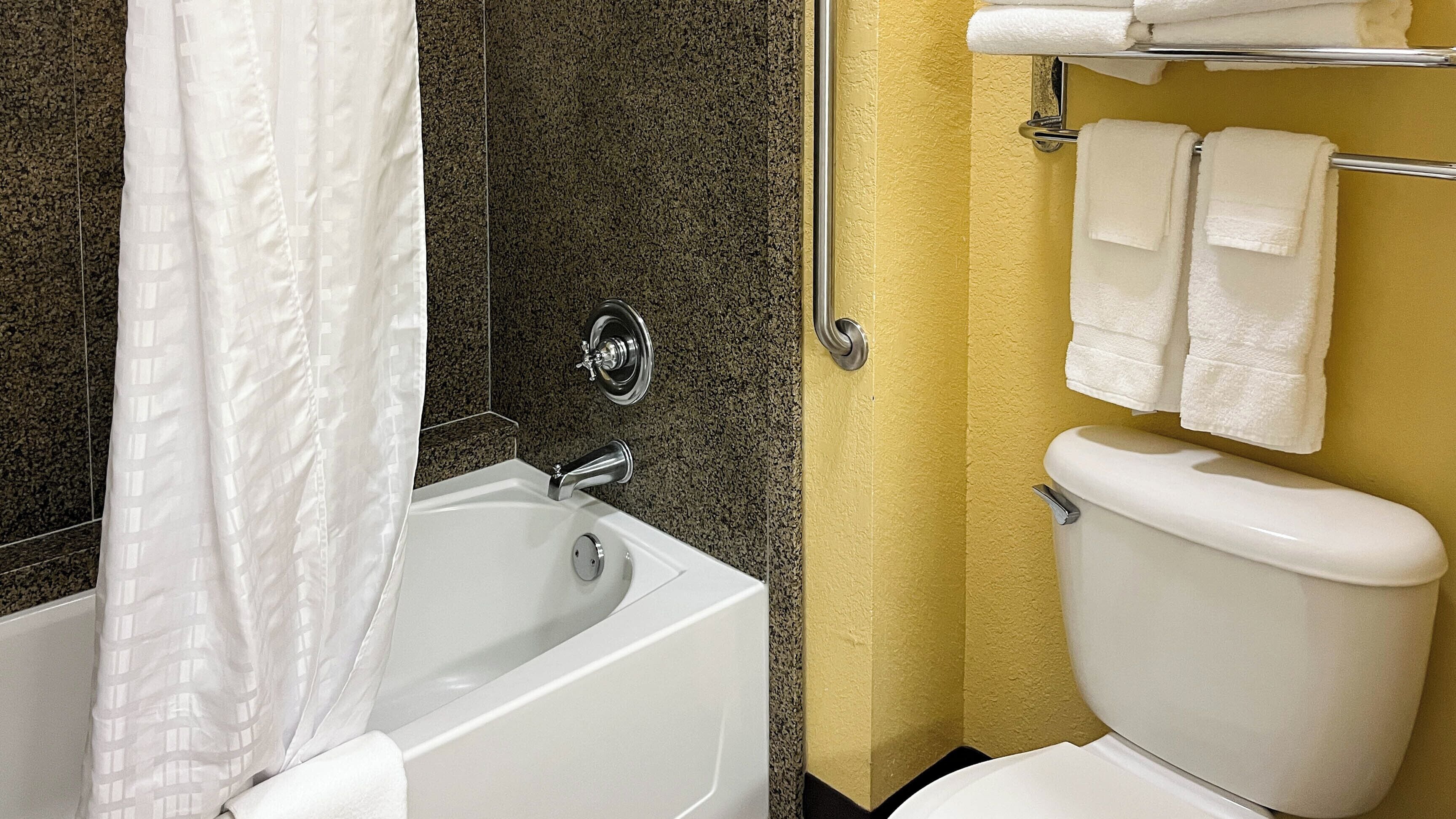 Un baño con bañera, inodoro y toallero.