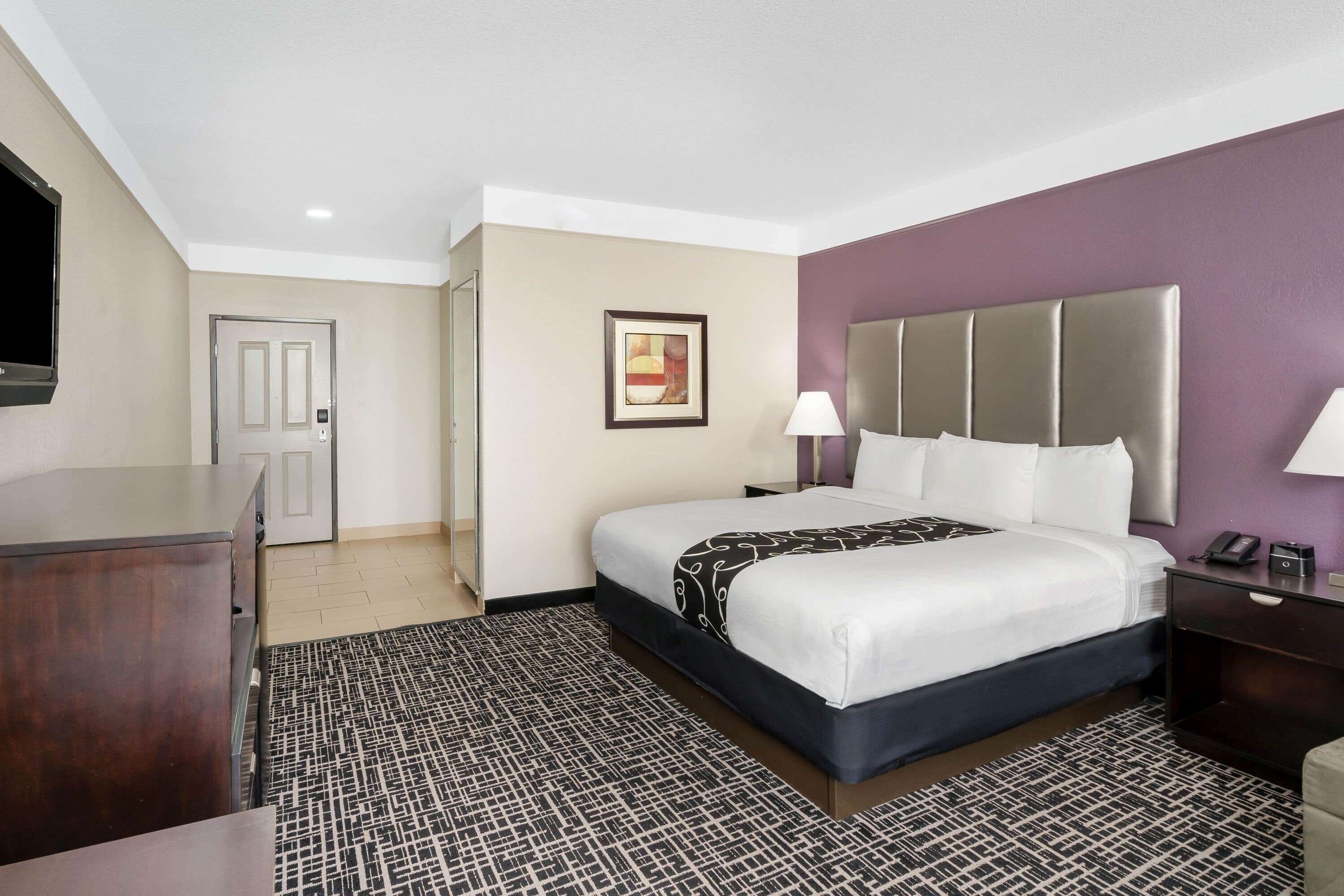 Une chambre d’hôtel avec un lit, une table de chevet, une lampe et un téléviseur posé sur un meuble.