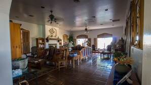 A spacious living room with a fireplace, multiple seating areas, and a large window providing natural light. - Casa de San Pedro Bed & Breakfast (Hereford)