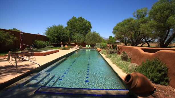 A rectangular swimming pool with clear blue water, surrounded by a landscaped garden with trees and shrubs. - Casa de San Pedro Bed & Breakfast (Hereford)
