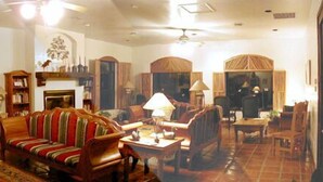 A living room with a striped sofa, a fireplace, and a dining area with a table and chairs. - Casa de San Pedro Bed & Breakfast (Hereford)
