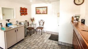 Una cocina con un lavamanos, armarios, un refrigerador y un comedor con dos sillas y una mesa.