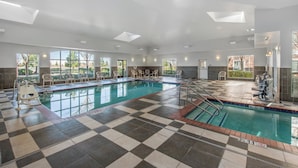 A large indoor swimming pool with a checkered floor, multiple windows, and a sunroof.