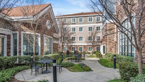 Un patio con mobiliario exterior, un edificio de ladrillo y cielo despejado.