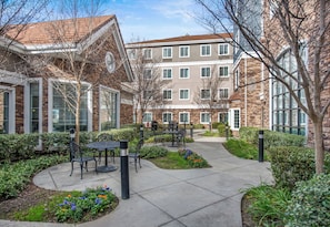A courtyard with outdoor seating, a brick building, and a clear sky.