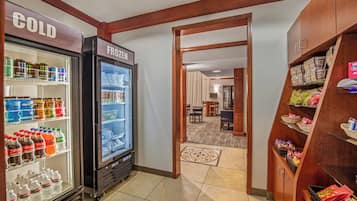 A hotel lobby with a cold drink refrigerator, a frozen food refrigerator, and a snack shelf.