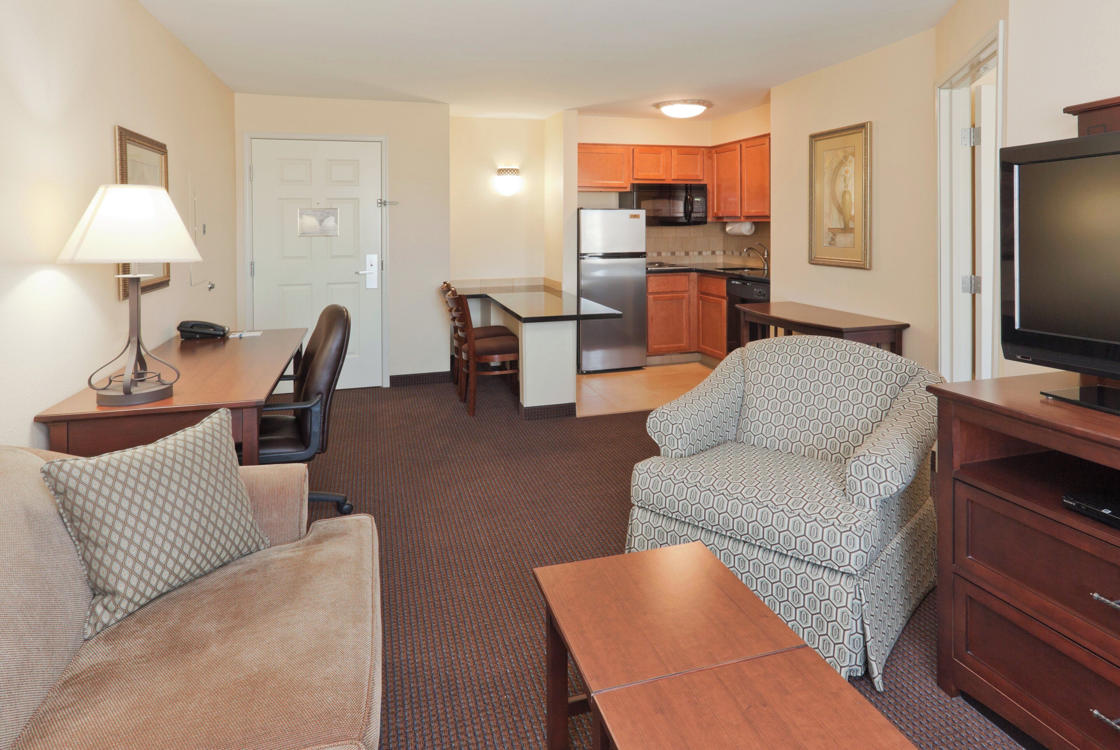 A compact living space with a kitchenette, a dining area, and a seating area with a sofa and armchair.