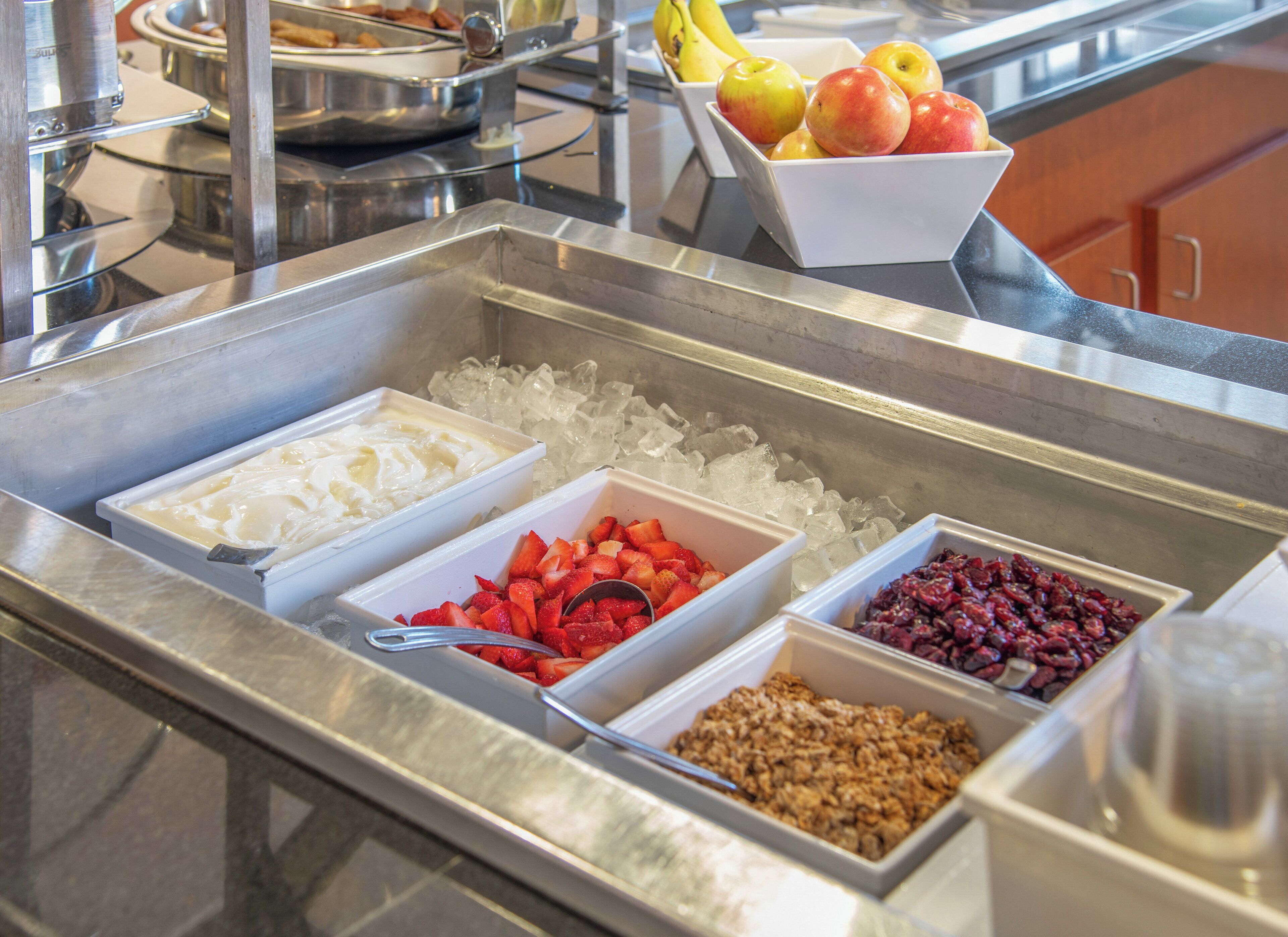 Ein Buffet mit verschiedenen Speisen, darunter Joghurt, Erdbeeren und Granola.