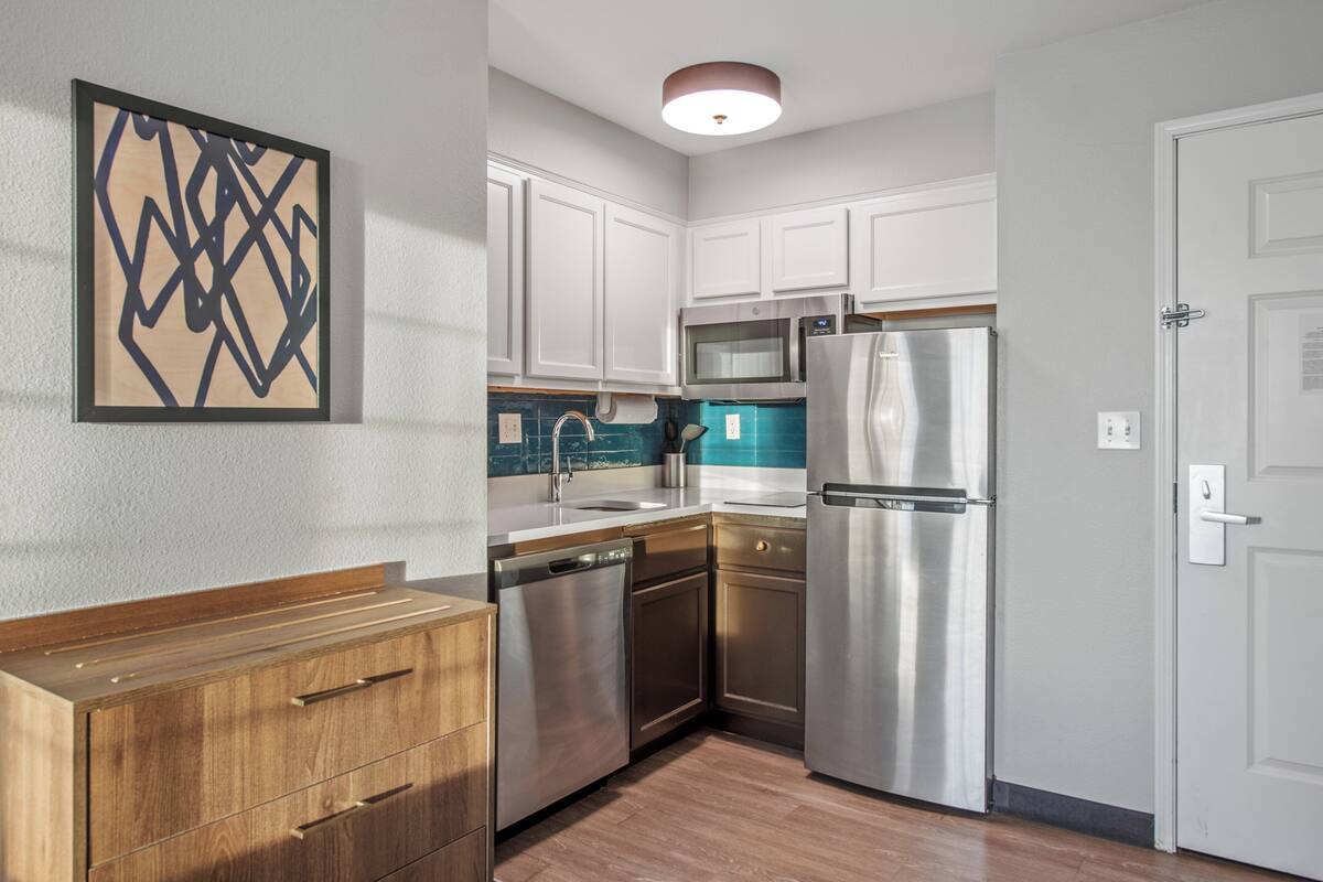 A modern kitchen with white cabinets, stainless steel appliances, and a wooden countertop.