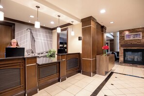 A reception area with a wooden reception desk, a potted plant, a fireplace, and a framed picture on the wall.