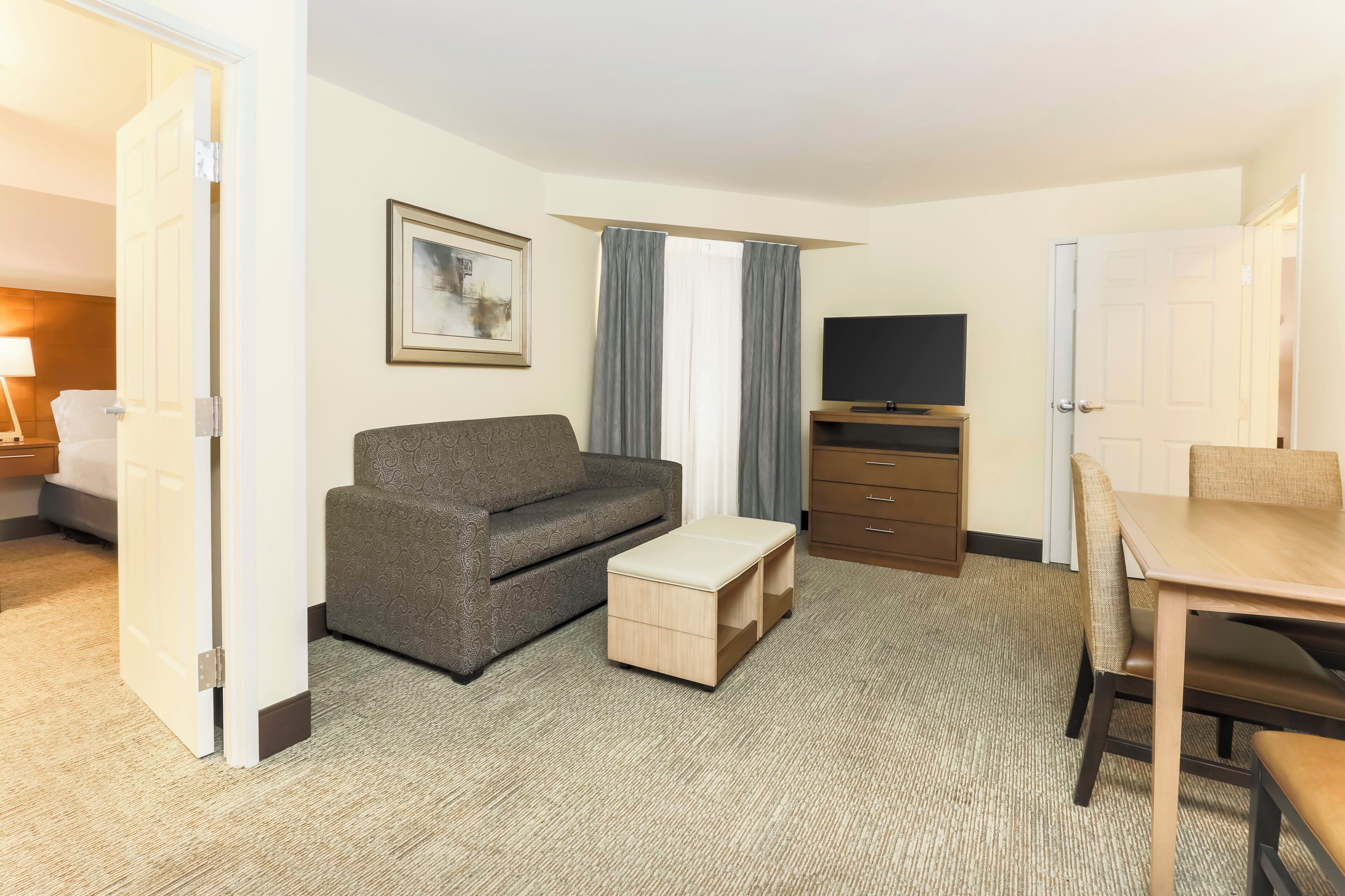 A hotel room with a sofa, a small table, a TV, and a wardrobe.