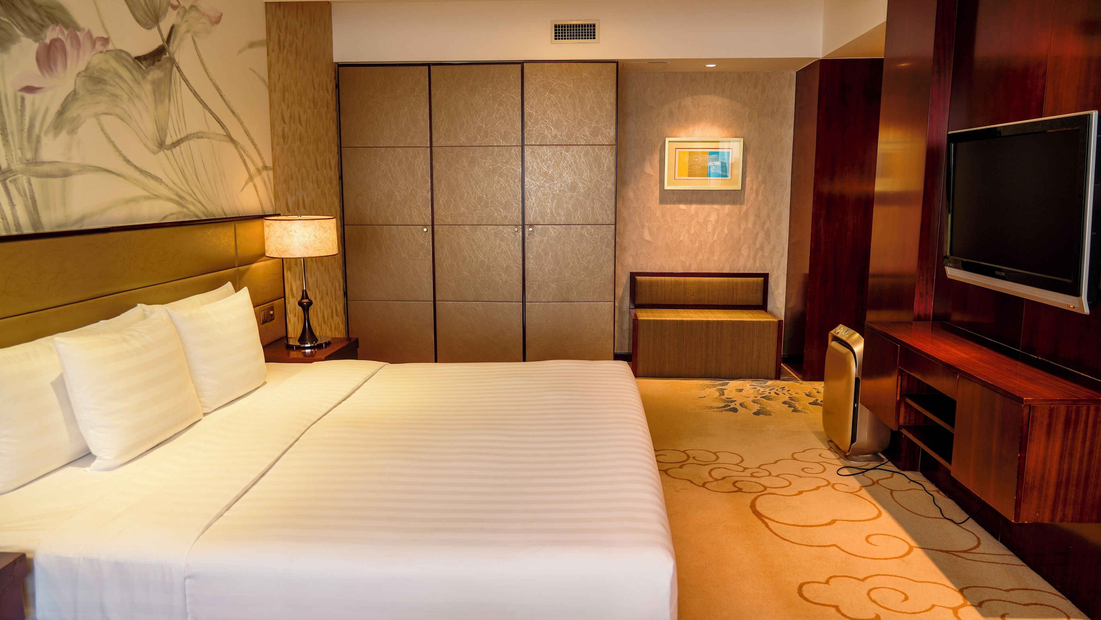 Una habitación de hotel con una cama grande, televisión, escritorio y zona de estar.