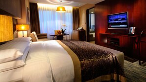 A hotel room with a large bed, a desk, a chair, a television, and a view of the city through the window. - Crowne Plaza Beijing Zhongguancun by IHG (Beijing)