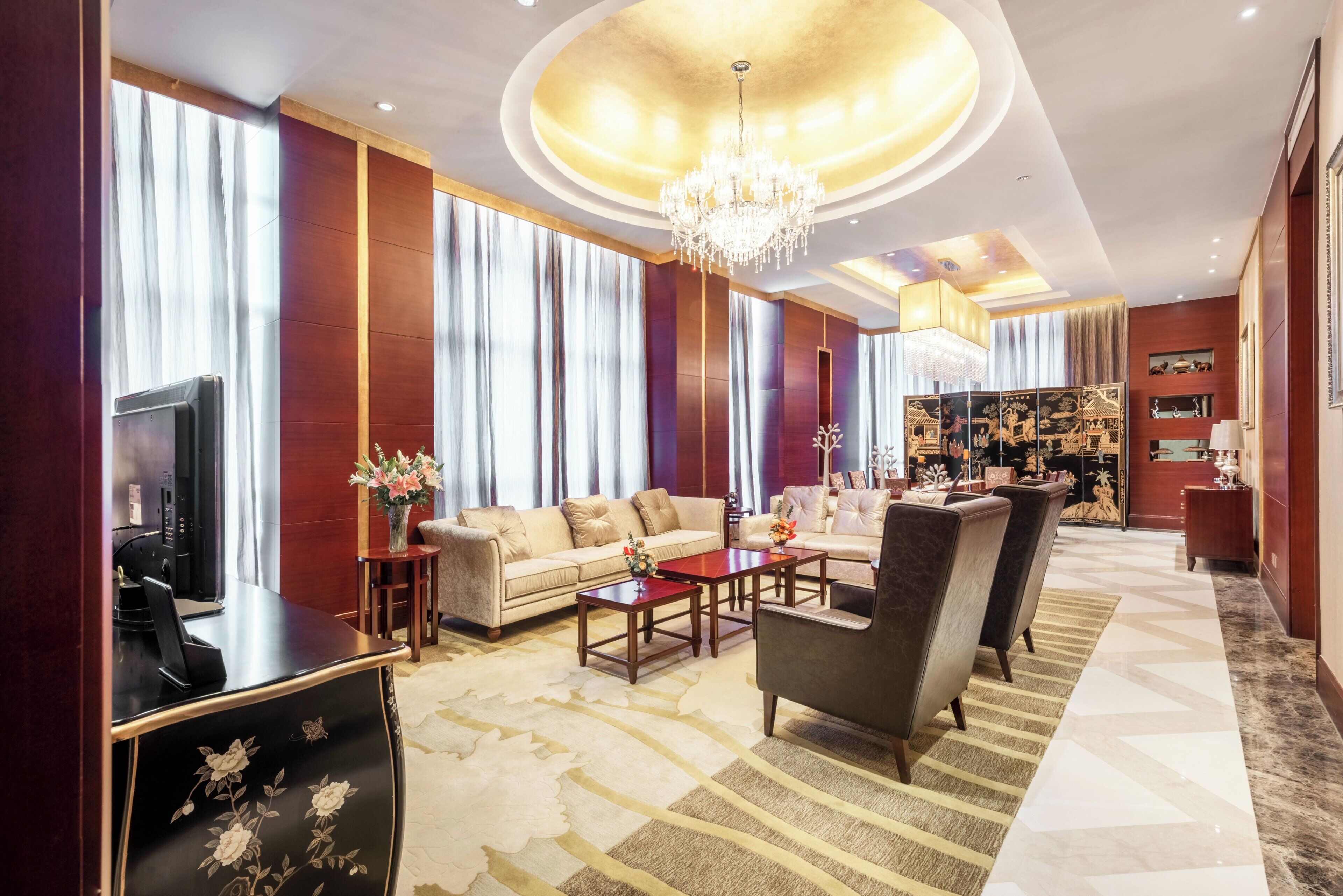 Un grand salon comprenant un canapé, des fauteuils, une table basse et un téléviseur.
