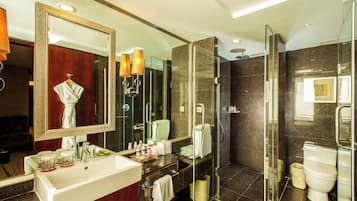 A modern bathroom with a large mirror, a sink, a glass shower enclosure, and a toilet.