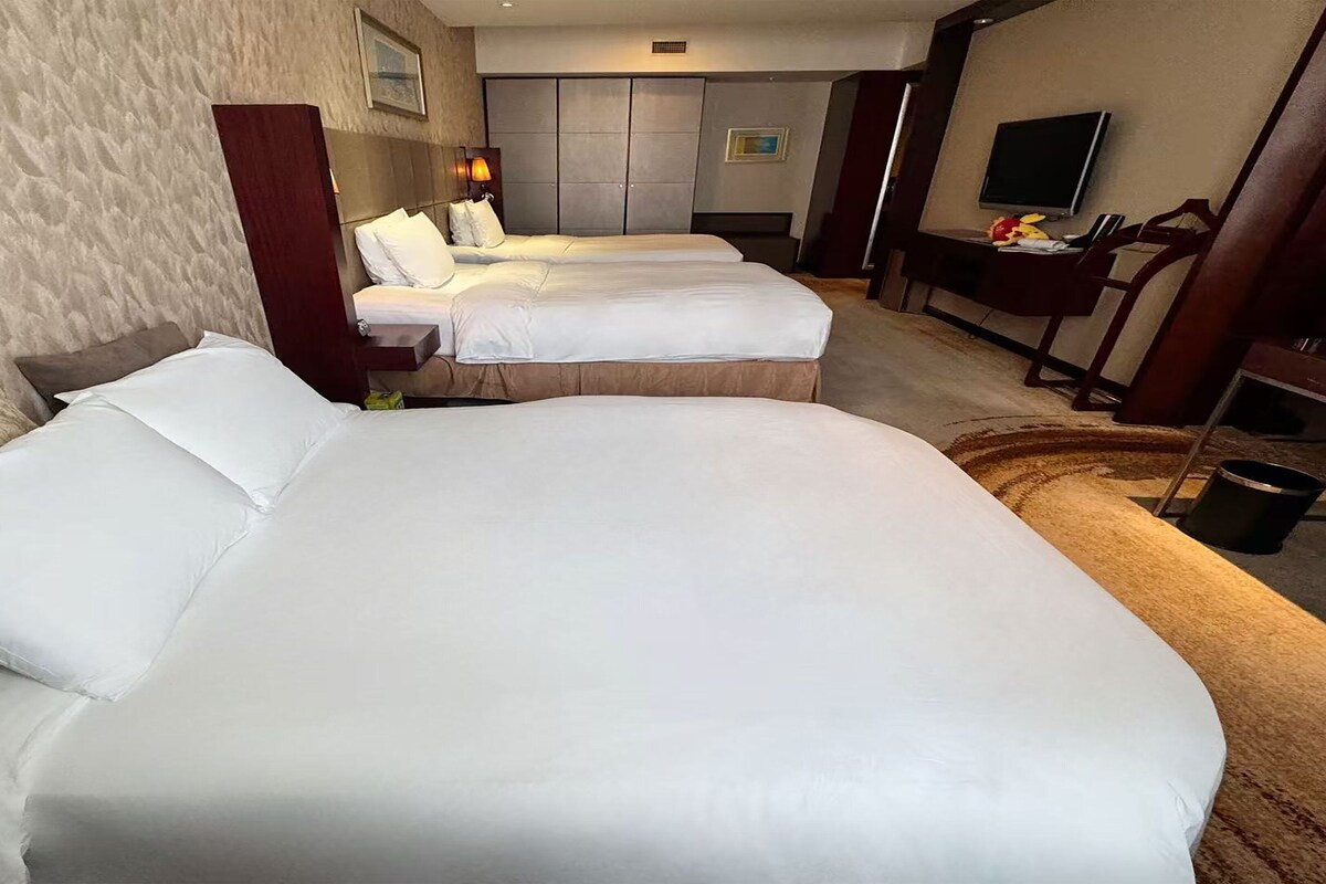 A hotel room with two beds, a TV, a desk, and a wardrobe.
