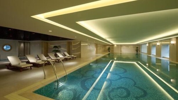 A modern indoor swimming pool with a geometric pattern on the floor, surrounded by lounge chairs and recessed lighting. - Crowne Plaza Beijing Zhongguancun by IHG (Beijing)