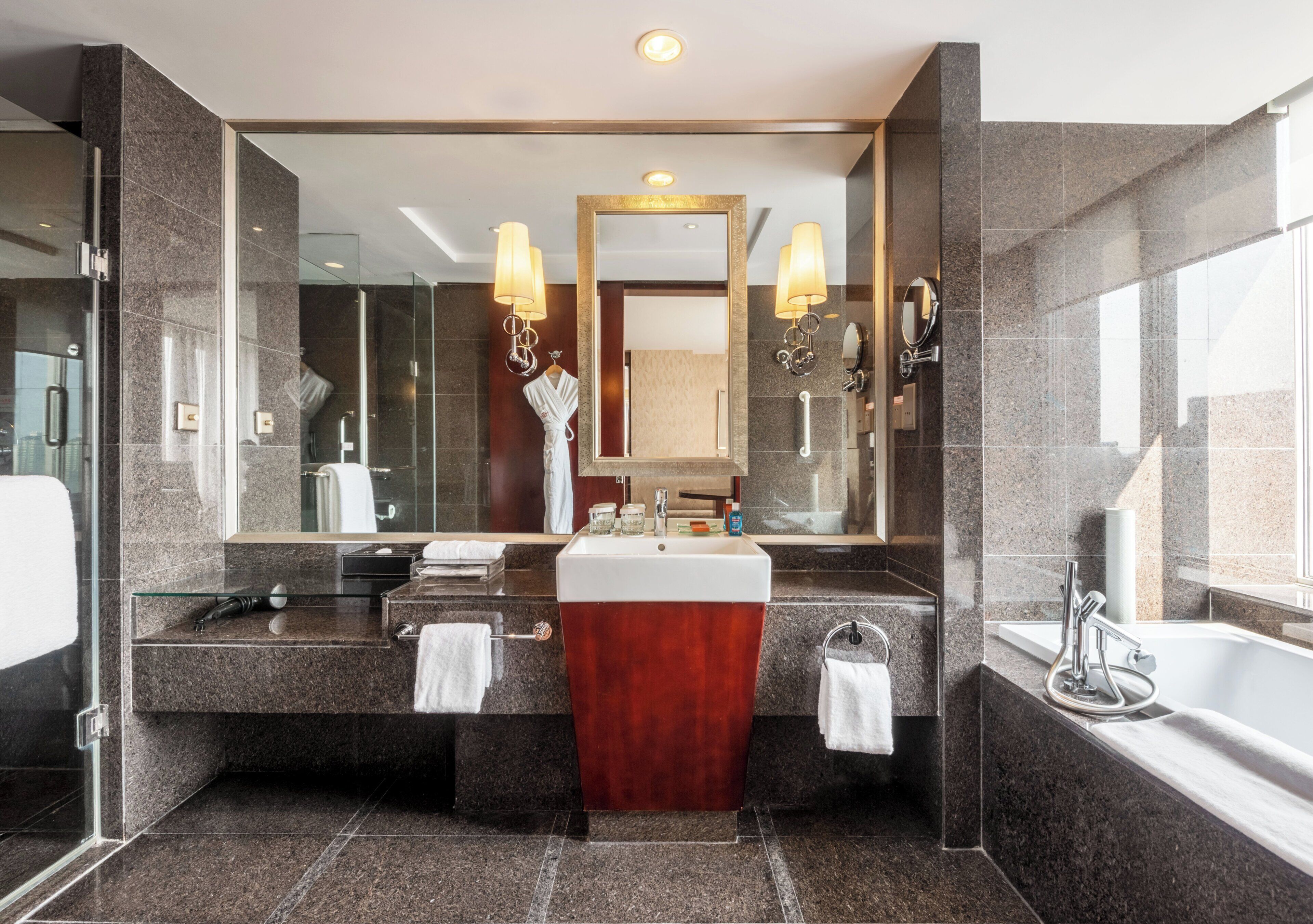 A modern bathroom with a large mirror, dual sinks, a vanity, and a bathtub.