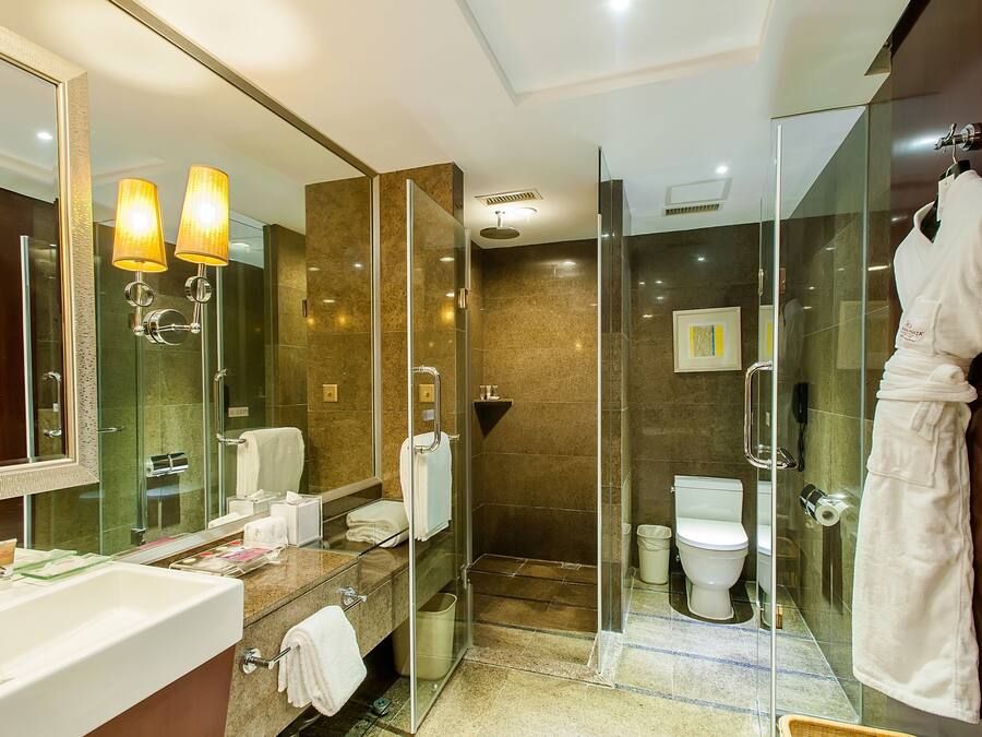 Un baño moderno con cabina de ducha de vidrio, un espejo grande y un lavamanos blanco.
