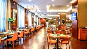 A spacious hotel dining area with multiple tables and chairs, a long corridor, and a television mounted on the wall. - Crowne Plaza Beijing Zhongguancun by IHG (Beijing)