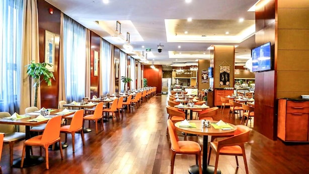 A spacious hotel dining area with multiple tables and chairs, a long corridor, and a television mounted on the wall. - Crowne Plaza Beijing Zhongguancun by IHG (Beijing)