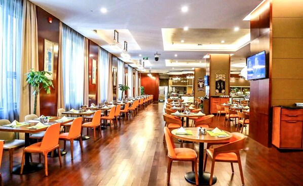 A spacious hotel dining area with multiple tables and chairs, a long corridor, and a television mounted on the wall. - Crowne Plaza Beijing Zhongguancun by IHG (Beijing)