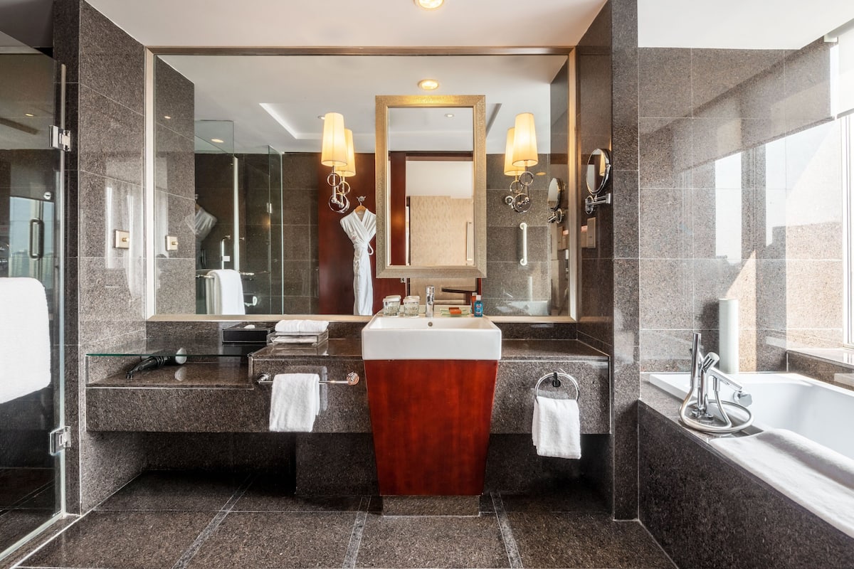 Ein modernes Badezimmer mit großem Spiegel, zwei Waschbecken, einem Waschtisch und einer Badewanne.