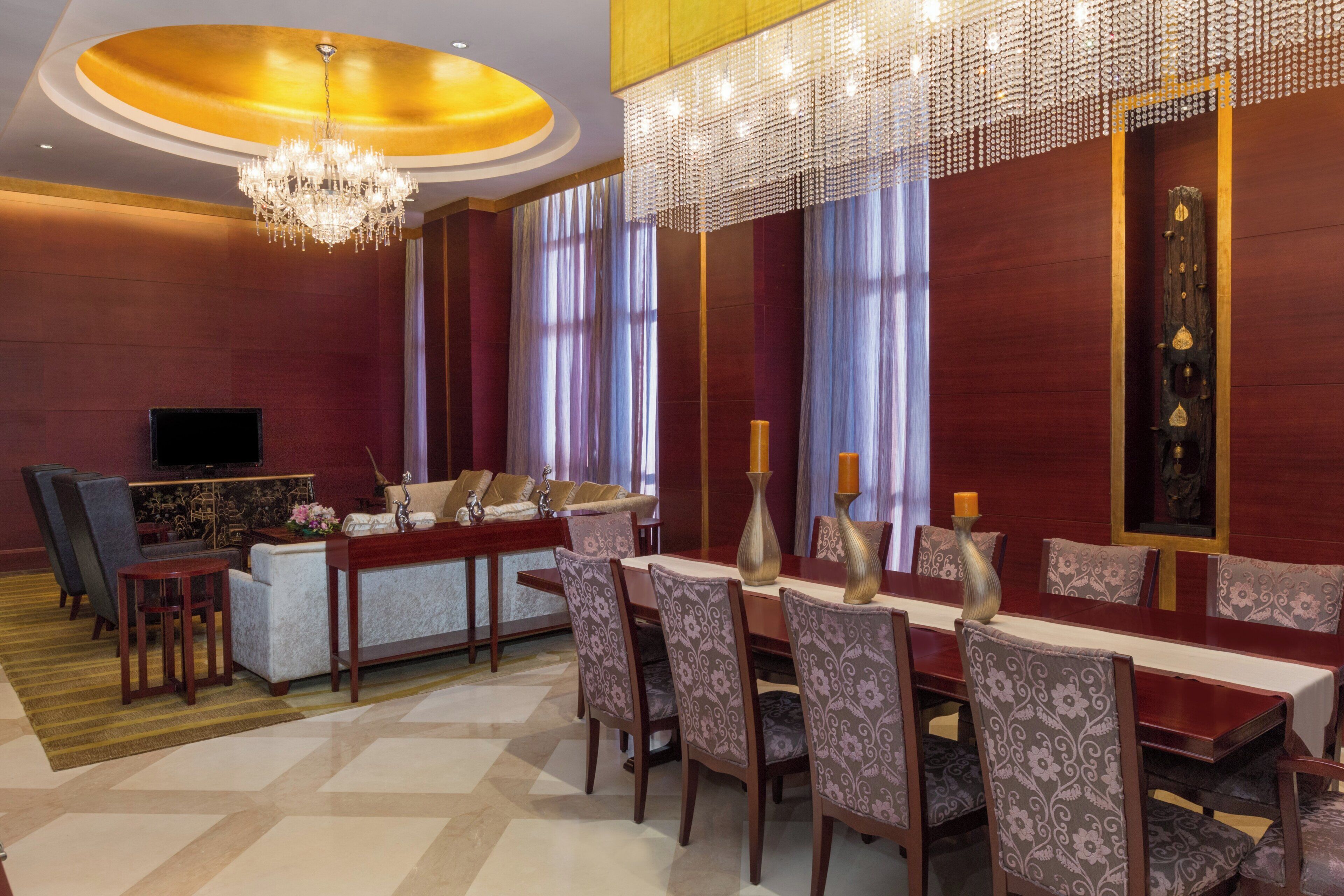 Habitación de hotel con comedor, televisor y candelabro.