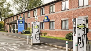 Ein Days Inn mit Ladestationen für Elektrofahrzeuge und einem Schild, das umweltfreundliche Unterkünfte kennzeichnet.