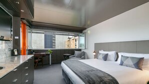 Moderni hotellihuone, jossa on suuri sänky, työpöytä ja näkymä kaupunkiin.