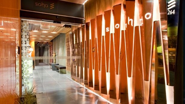 Moderni hotellikäytävä, jossa on tyylikäs muotoilu. Käytävällä on vastaanottoalue, jossa on näkyvillä kyltti, jossa lukee ”Soho”, ja seinässä on numero ”264”.