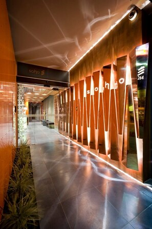 Corredor moderno de hotel, com design elegante, apresenta uma área de recepção com o letreiro 'soho' e o número '264' na parede.