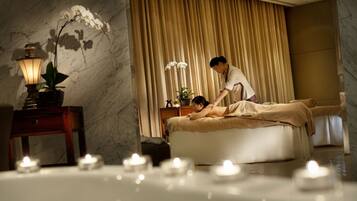 Experience a serene spa setting with a massage table at its center, surrounded by candles and a calming atmosphere.