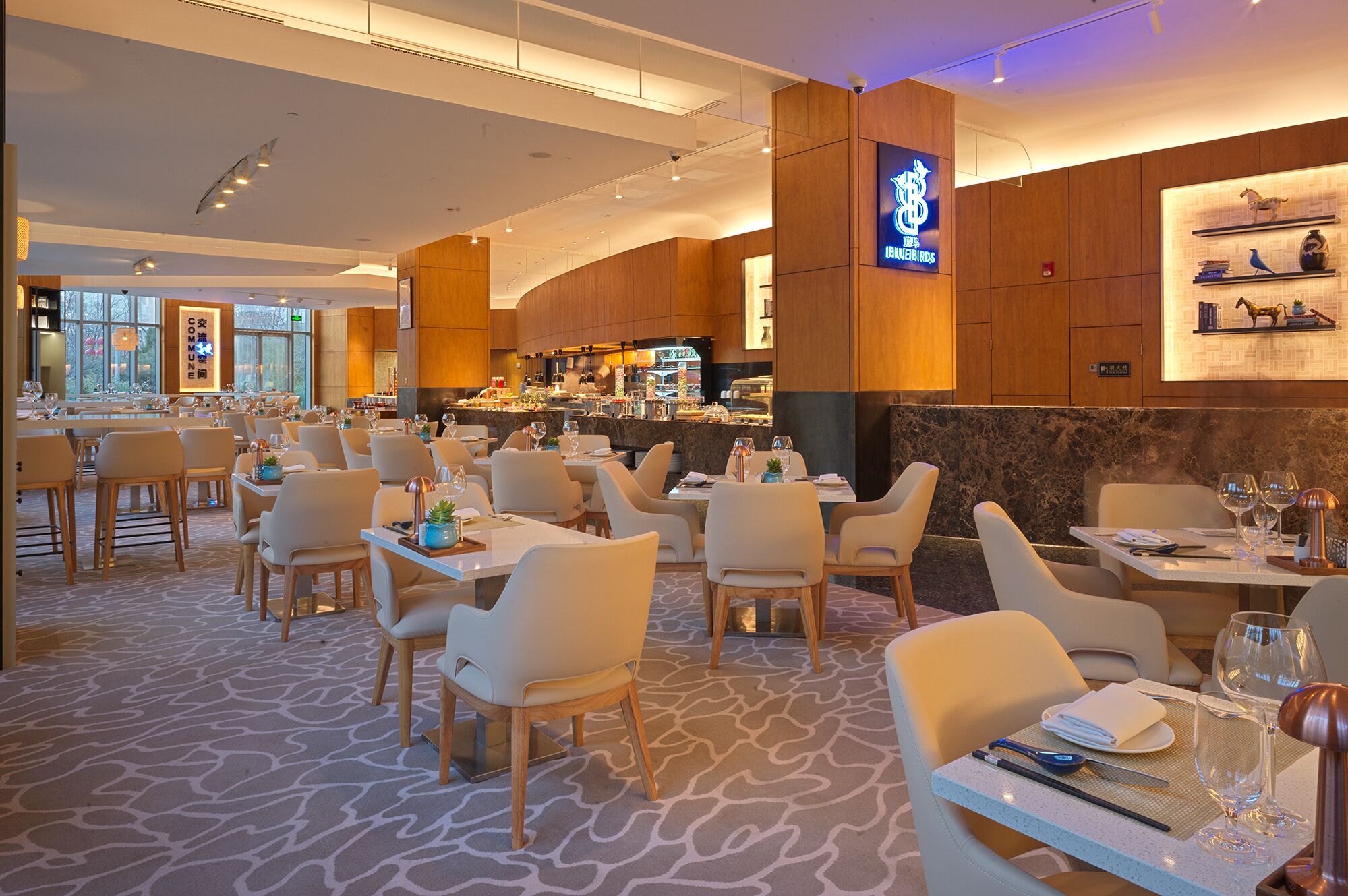 A modern restaurant with a bar area, multiple dining tables, and chairs.