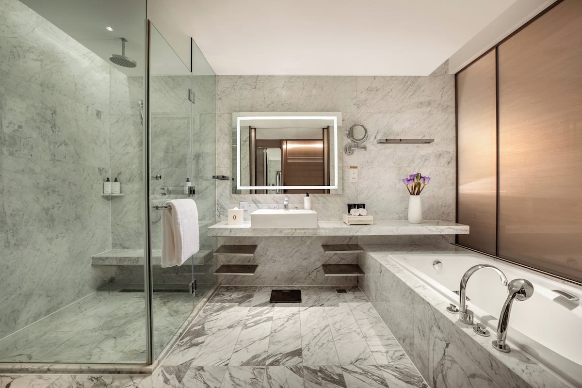 A modern bathroom with a glass-enclosed shower, a large freestanding bathtub, and a vanity with a mirror.