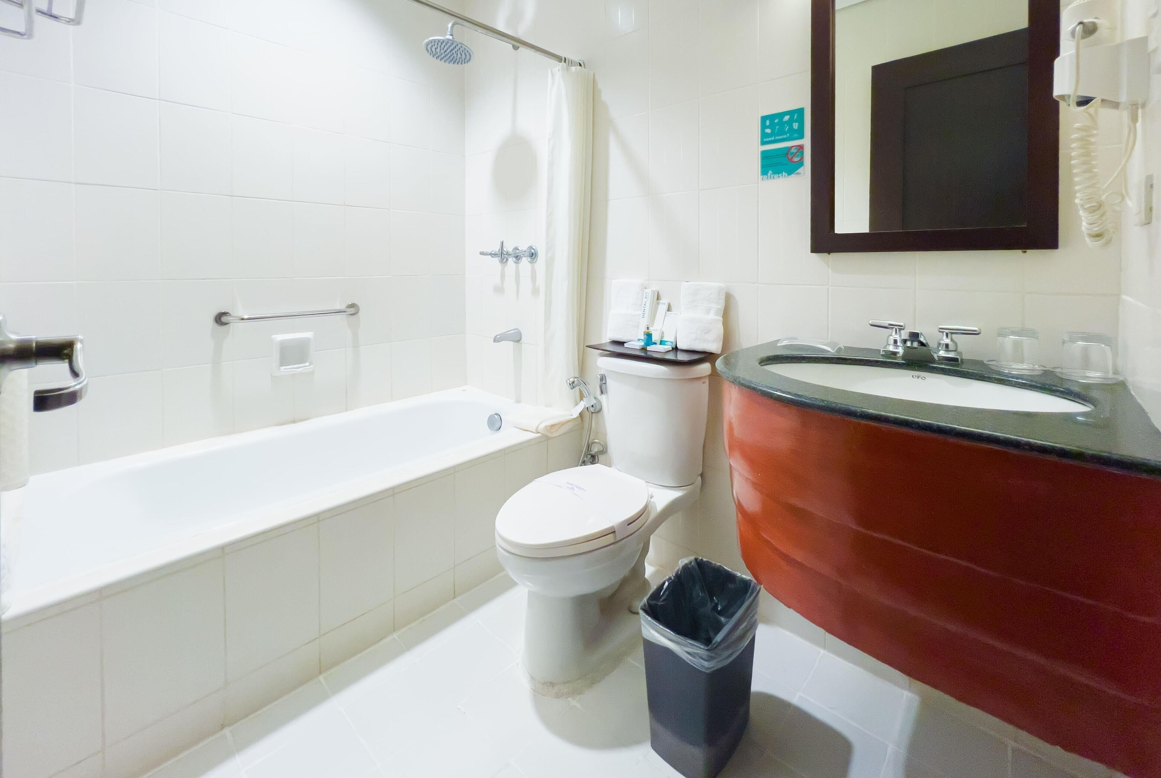 Une salle de bain équipée d’une baignoire, de toilettes, d’un lavabo et d’une poubelle.