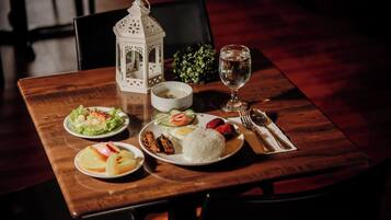 A dining table with plates of food, a glass of water, and a white lantern.