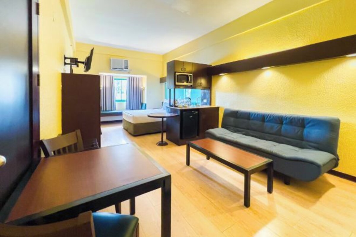 A compact living space with a sofa, a dining table, and a kitchenette area.