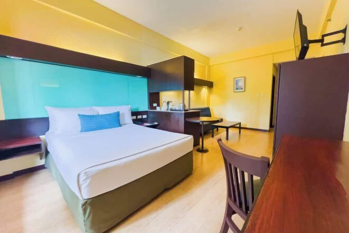 Ein Hotelzimmer mit Bett, Schreibtisch, Stuhl und Fernseher.