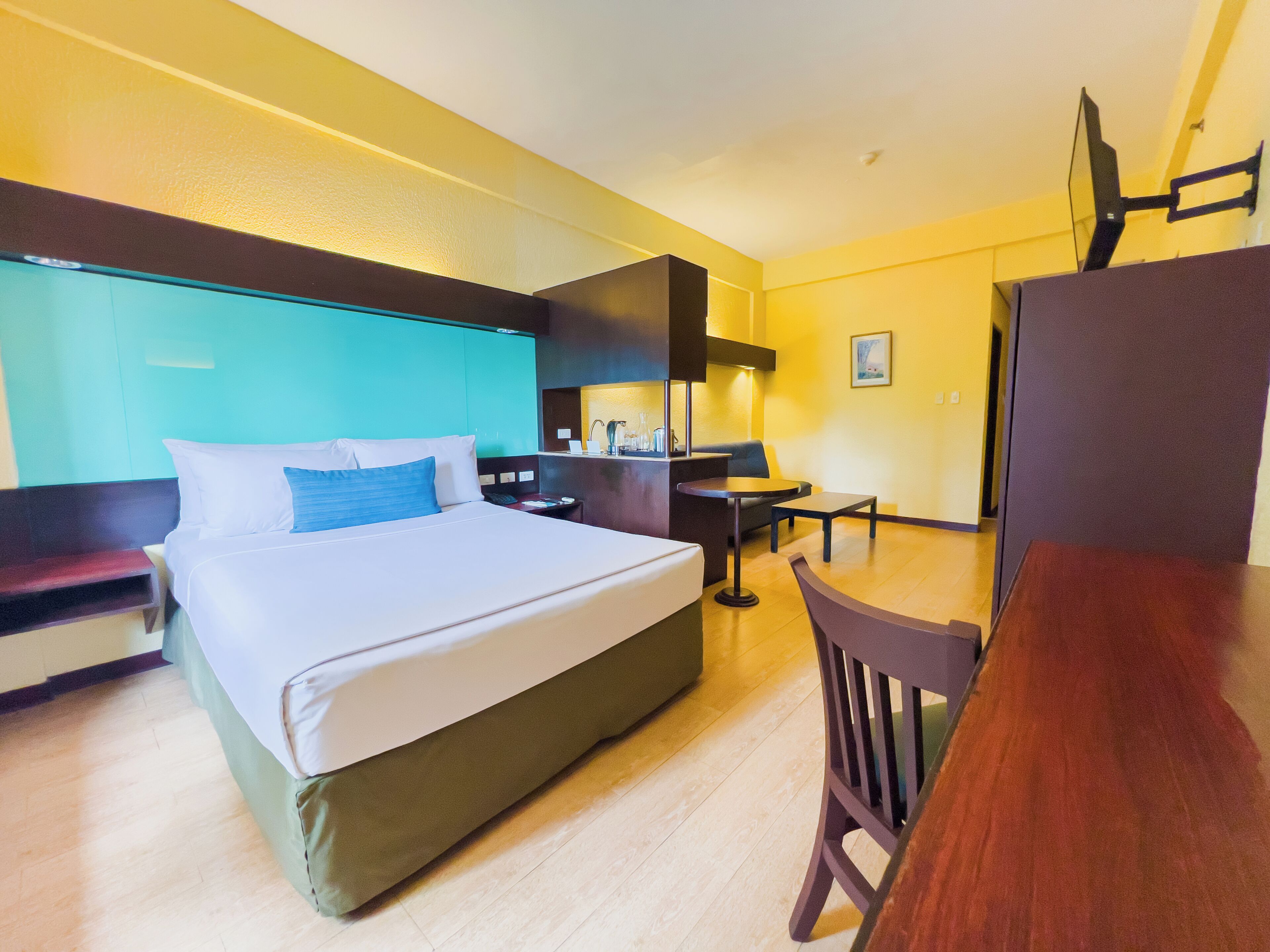 Una habitación de hotel con cama, escritorio, silla y televisor.