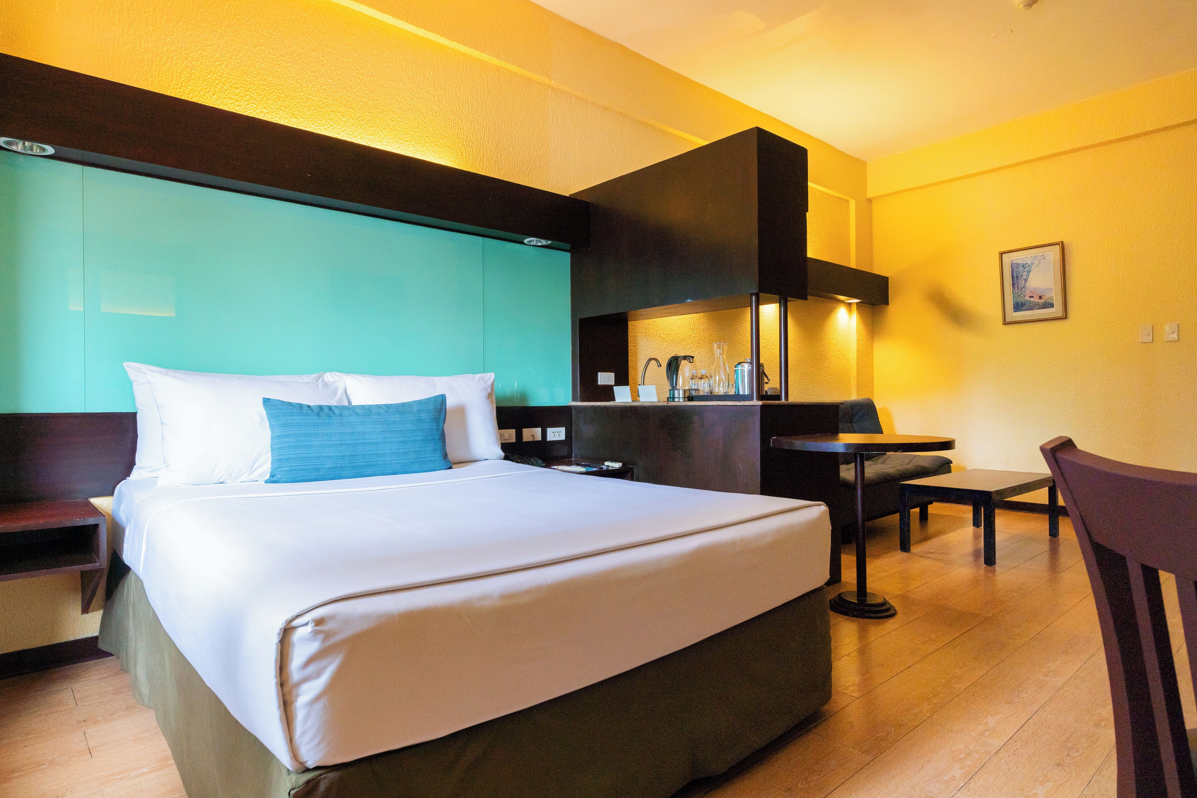 A hotel room with a large bed, a desk, and a chair.