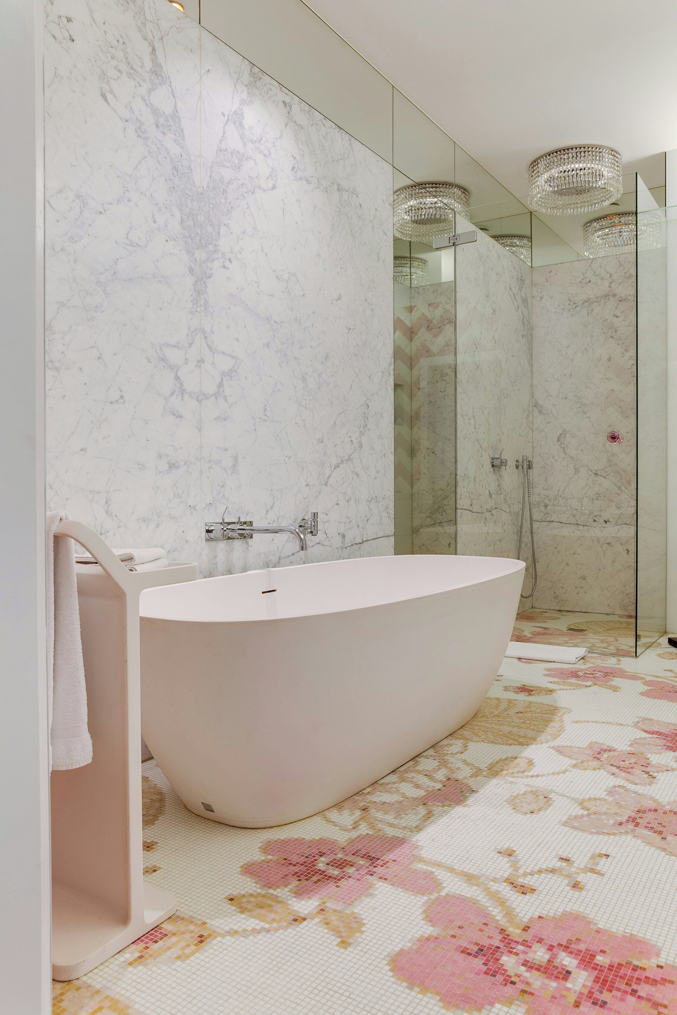 A modern bathroom with a freestanding bathtub, a glass shower enclosure, and a marble wall.