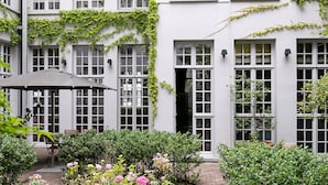 Un edificio blanco con múltiples ventanas y un patio techado con mesa y sillas.